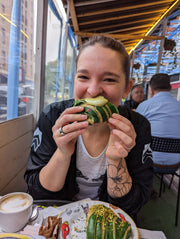 A woman eating a taco and enjoying a heart-shaped foam coffee, capturing a moment of nourishment and relaxation.